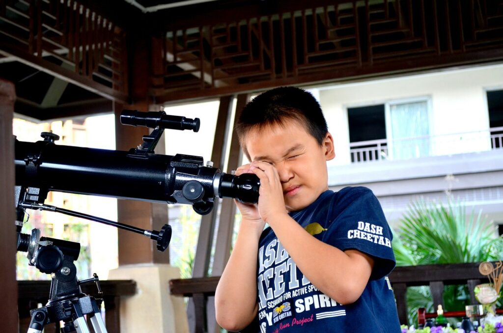 small child looking through a telescope