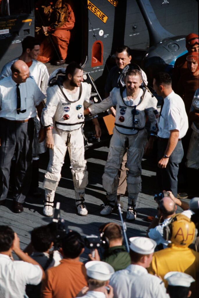 Astronauts James A. Lovell Jr. (left), Gemini-7 pilot, and Frank Borman, command pilot, are shown just after they arrived aboard the aircraft carrier USS Wasp. Greeting the astronauts are Donald Stullken (at Lovell's right), Recovery Operations Branch, Landing and Recovery Division, Dr. Howard Minners (standing beside Borman), Flight Medicine Branch, Center Medical Office, Manned Spacecraft Center, and Bennett James (standing behind Borman), a NASA Public Affairs Officer. The National Aeronautics and Space Administration's Gemini-7 spacecraft splashed down in the western Atlantic recovery area at 9:05 a.m. (EST), Dec. 18, 1965, to conclude a record-breaking 14-day mission in space. Photo credit: NASA